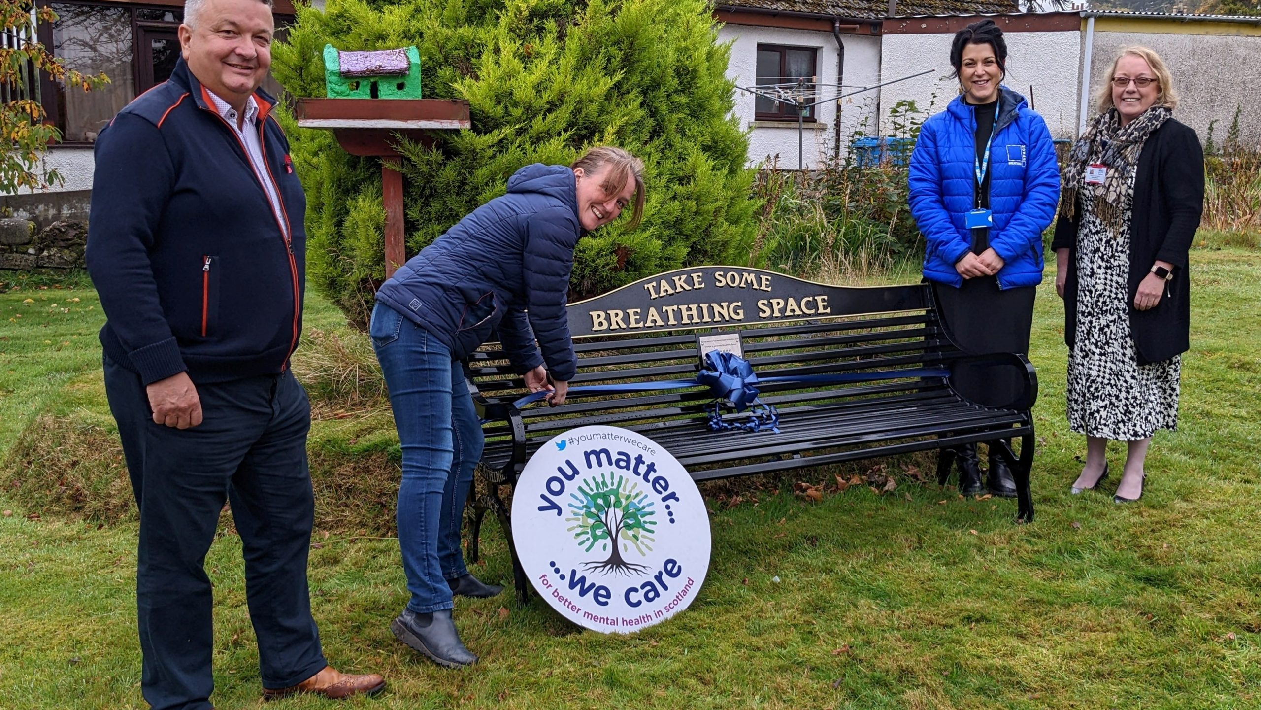 4 people smiling around bench